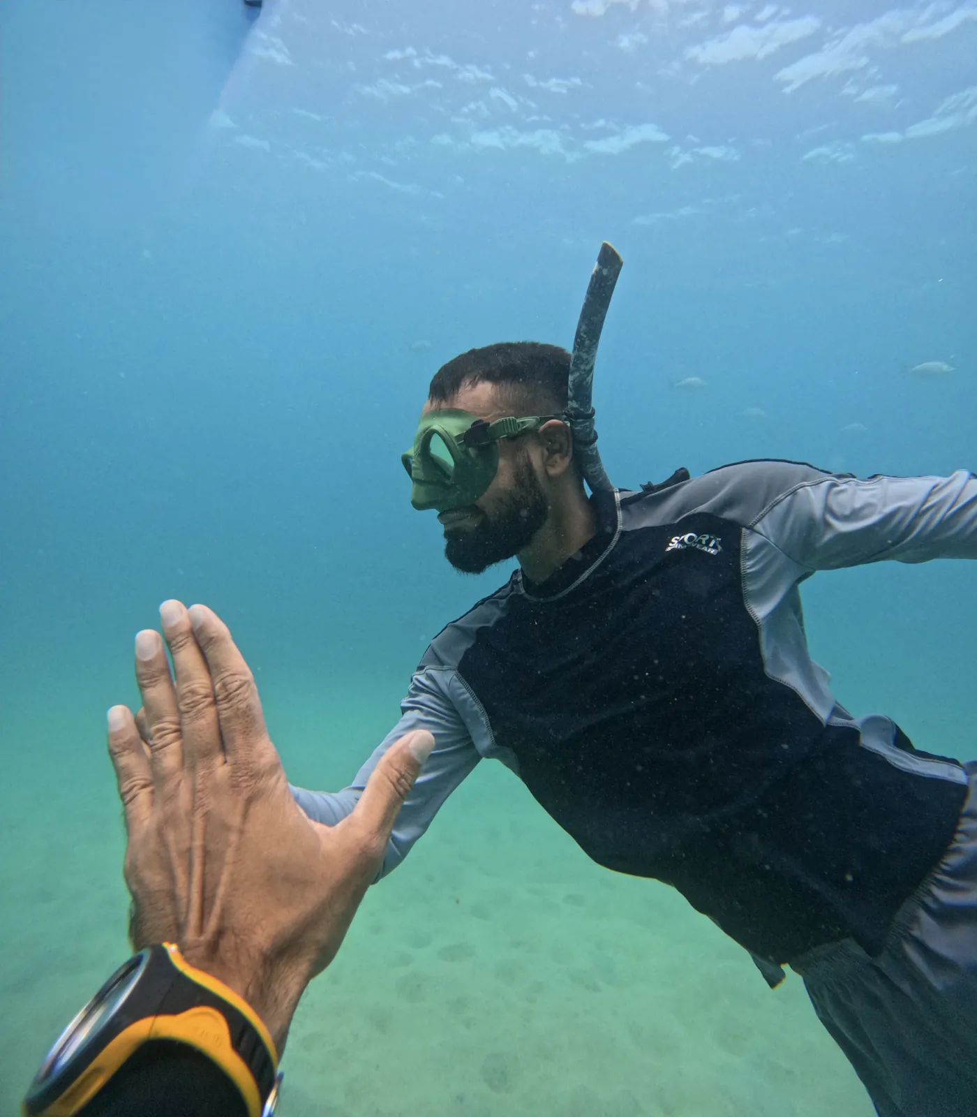 Freediver and instructor meeting hands underwater during a session in Koh Tao